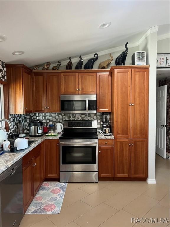 kitchen with sink, stainless steel appliances, light stone counters, decorative backsplash, and light tile patterned flooring