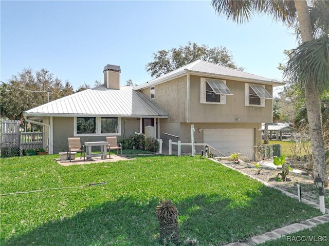 rear view of property featuring a garage and a lawn