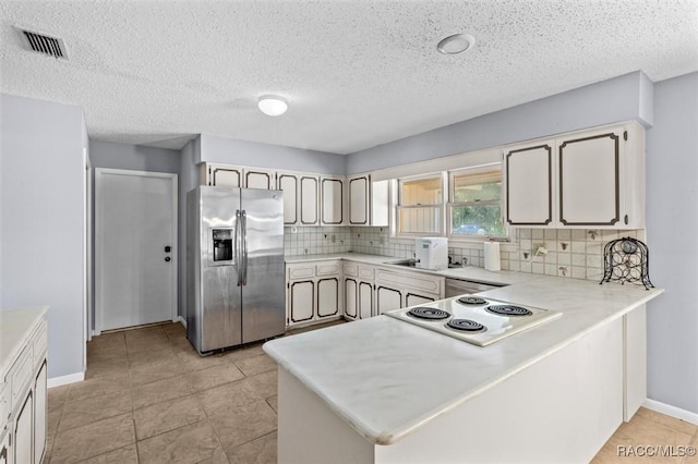 kitchen featuring kitchen peninsula, stainless steel fridge, backsplash, and white electric cooktop