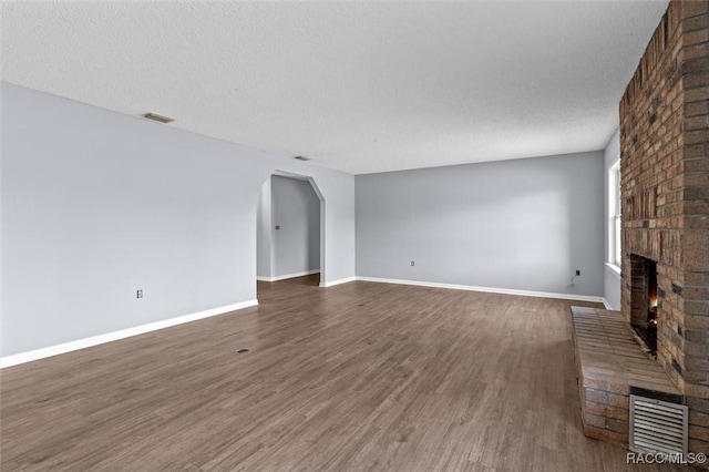 unfurnished living room featuring a fireplace, a textured ceiling, and dark hardwood / wood-style floors