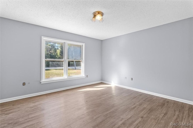 empty room with hardwood / wood-style flooring and a textured ceiling