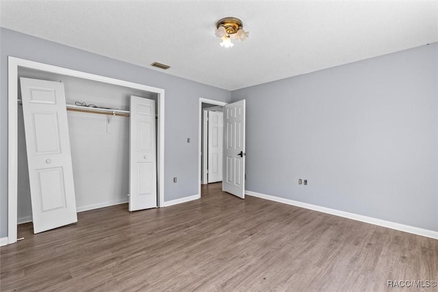 unfurnished bedroom featuring a textured ceiling, dark hardwood / wood-style floors, and a closet