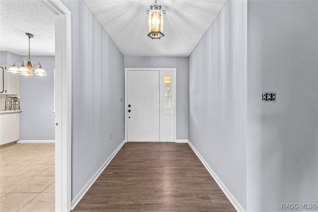 entrance foyer featuring a textured ceiling, hardwood / wood-style flooring, and an inviting chandelier