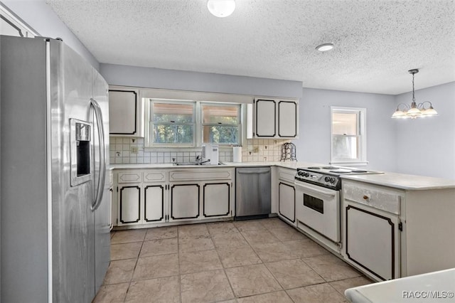 kitchen with pendant lighting, plenty of natural light, backsplash, and stainless steel appliances