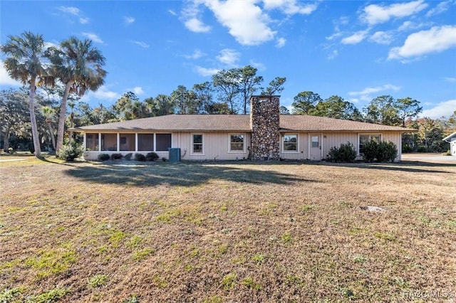 back of house featuring a sunroom and a lawn