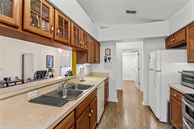 kitchen with white appliances, visible vents, brown cabinetry, glass insert cabinets, and light countertops