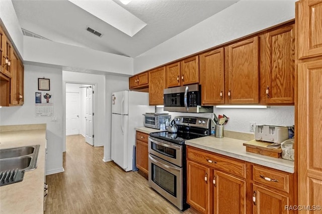 kitchen featuring stainless steel appliances, light countertops, and brown cabinets