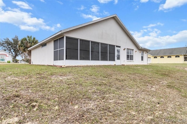 rear view of house with a lawn and stucco siding