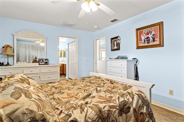 bedroom featuring ceiling fan, connected bathroom, visible vents, and light wood-style floors