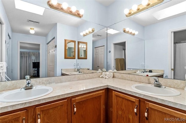 bathroom with a closet, a skylight, vanity, and visible vents