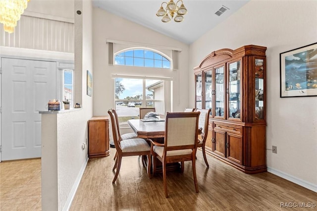 dining space with baseboards, light wood finished floors, visible vents, and an inviting chandelier