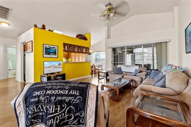 living area featuring lofted ceiling, ceiling fan, visible vents, and wood finished floors