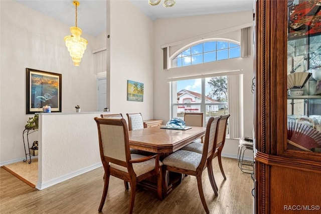 dining space with baseboards, light wood finished floors, and an inviting chandelier