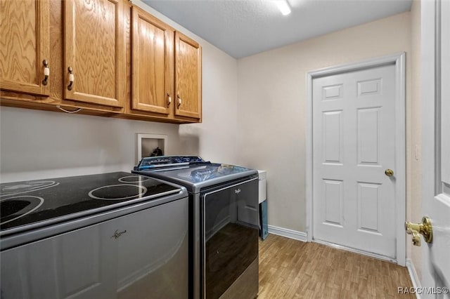 laundry area with light wood-style flooring, washer and clothes dryer, cabinet space, and baseboards