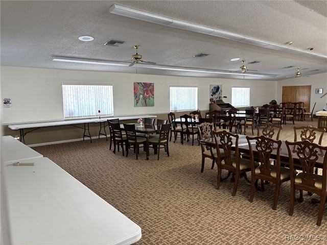 carpeted dining area with baseboards, ceiling fan, visible vents, and a textured ceiling