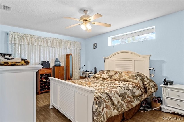 bedroom featuring a textured ceiling, ceiling fan, dark wood-style flooring, and visible vents