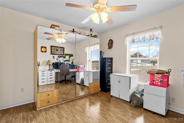 home office featuring light wood-type flooring, ceiling fan, and baseboards