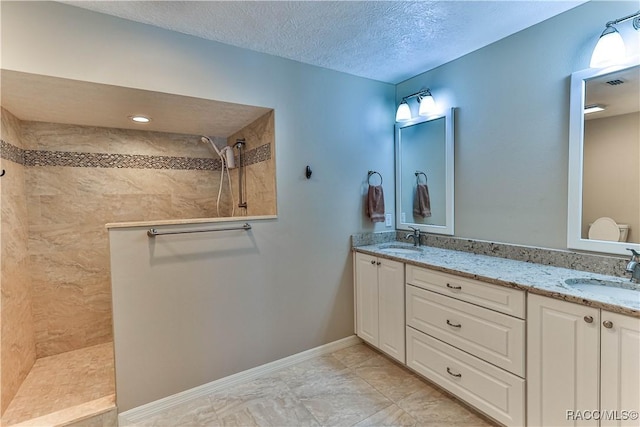 bathroom featuring double vanity, tiled shower, and a sink