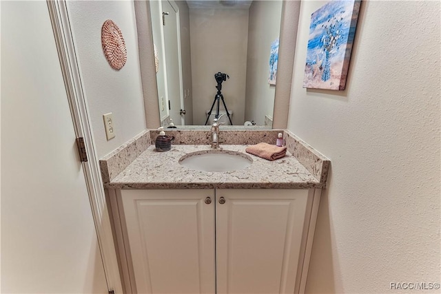 bathroom with a textured wall and vanity