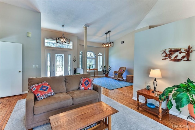 living area featuring visible vents, baseboards, wood finished floors, a textured ceiling, and ornate columns