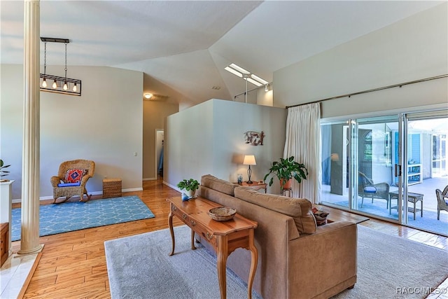 living room with high vaulted ceiling, light wood-type flooring, and baseboards