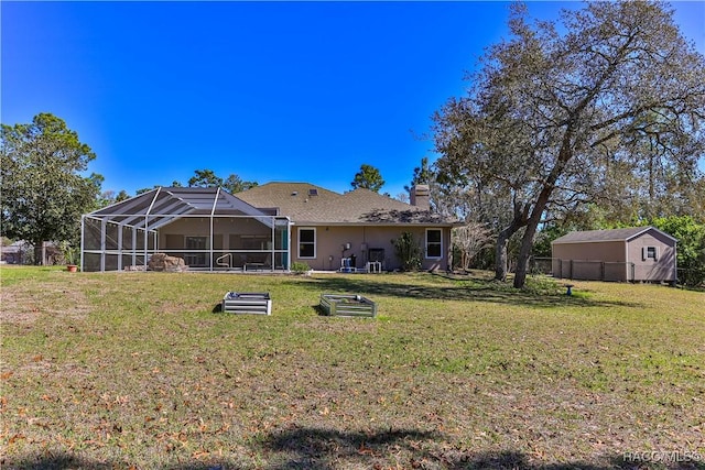 rear view of house with glass enclosure, a chimney, fence, and a lawn