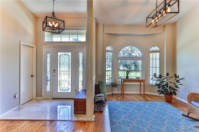 entryway featuring a chandelier, hardwood / wood-style flooring, and baseboards