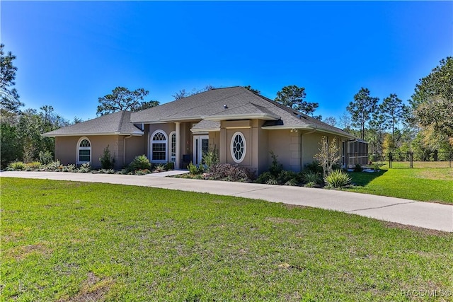 ranch-style home featuring driveway, fence, a front lawn, and stucco siding