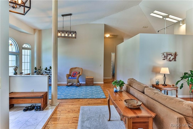 living room with lofted ceiling, light wood-style floors, and baseboards