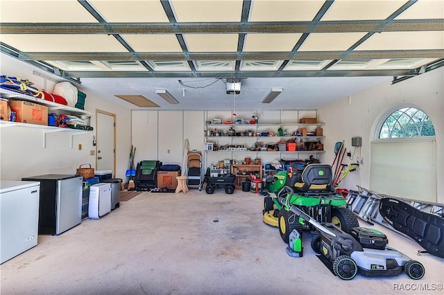 garage featuring fridge, freestanding refrigerator, and a garage door opener