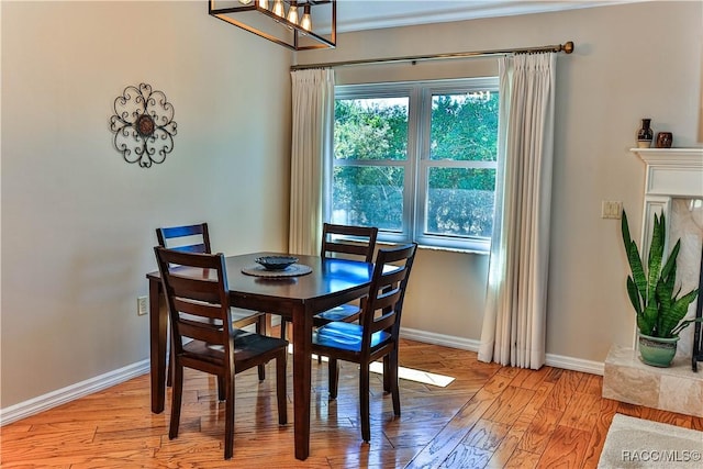 dining room featuring a chandelier, light wood-type flooring, and baseboards