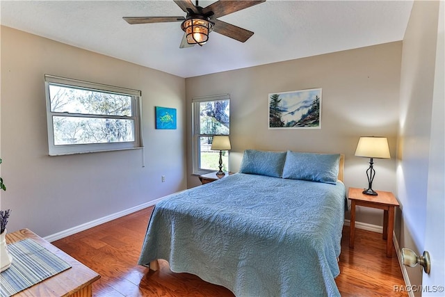 bedroom with ceiling fan, wood finished floors, and baseboards