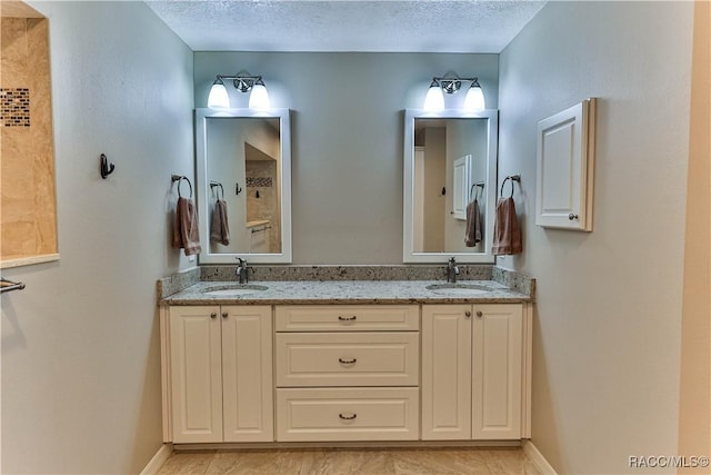 bathroom featuring a sink, a textured ceiling, baseboards, and double vanity