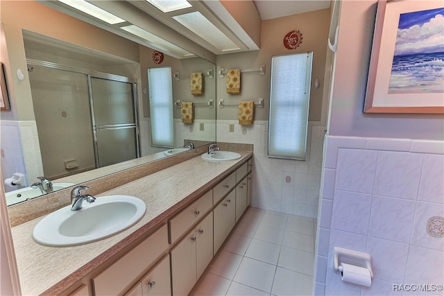 full bath with tile walls, double vanity, a stall shower, a sink, and tile patterned floors