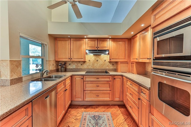 kitchen with stainless steel appliances, backsplash, a sink, and under cabinet range hood