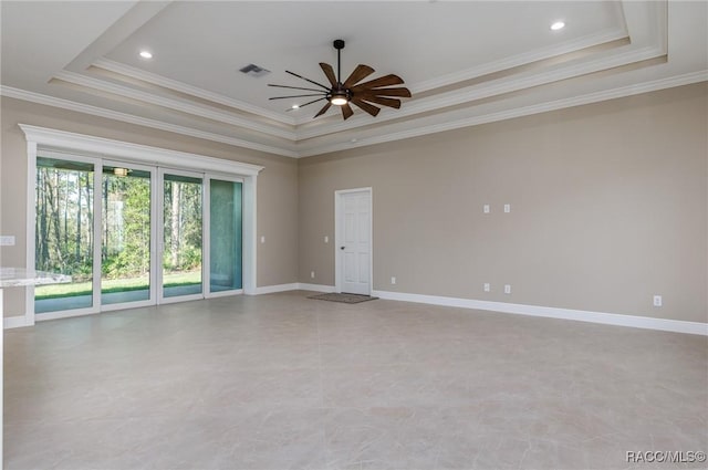 spare room with a raised ceiling, a ceiling fan, visible vents, and baseboards