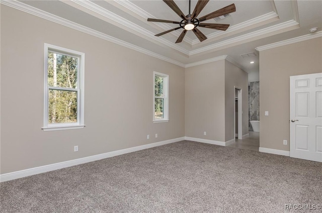 empty room with a ceiling fan, carpet, baseboards, crown molding, and a raised ceiling