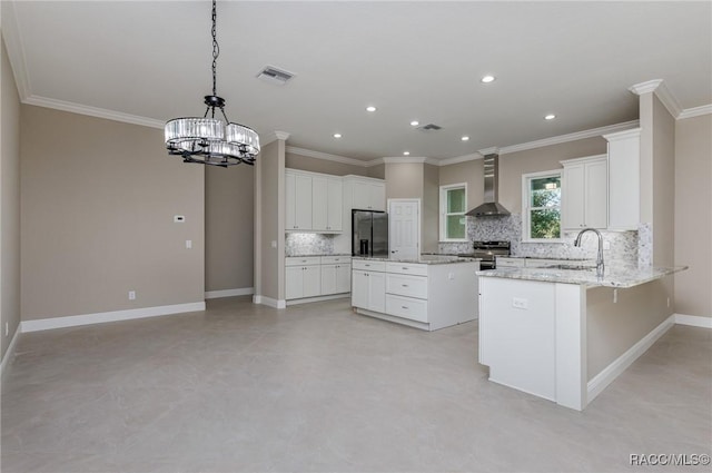 kitchen with a sink, stainless steel appliances, an inviting chandelier, wall chimney range hood, and baseboards