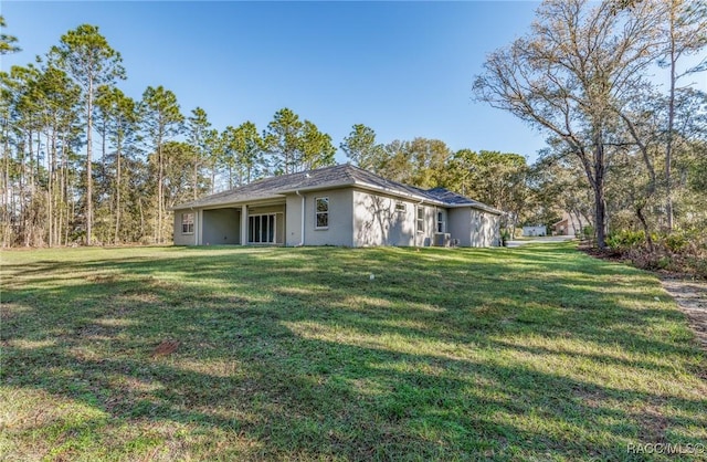 rear view of property featuring stucco siding and a yard