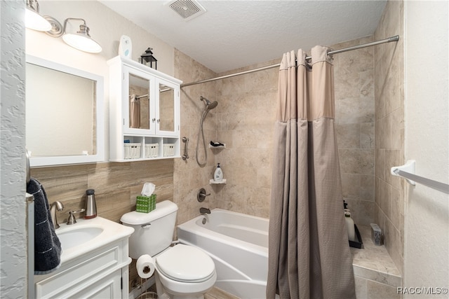 full bathroom with shower / tub combo, vanity, a textured ceiling, tile walls, and toilet