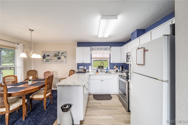 kitchen with pendant lighting, plenty of natural light, white cabinets, and appliances with stainless steel finishes