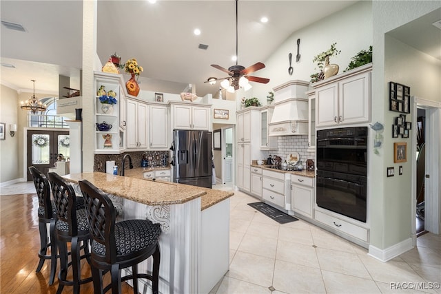 kitchen featuring tasteful backsplash, kitchen peninsula, a breakfast bar area, black appliances, and ceiling fan with notable chandelier