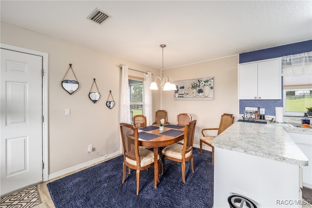 dining space with dark hardwood / wood-style floors, an inviting chandelier, and a healthy amount of sunlight