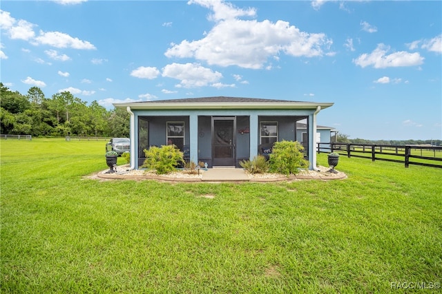 view of outdoor structure featuring a sunroom, a rural view, and a lawn