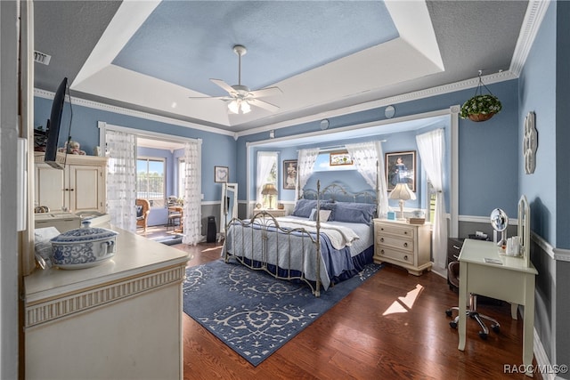 bedroom with a tray ceiling, crown molding, ceiling fan, and dark wood-type flooring