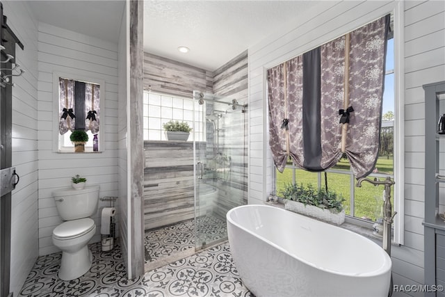 bathroom with shower with separate bathtub, toilet, a wealth of natural light, and wood walls