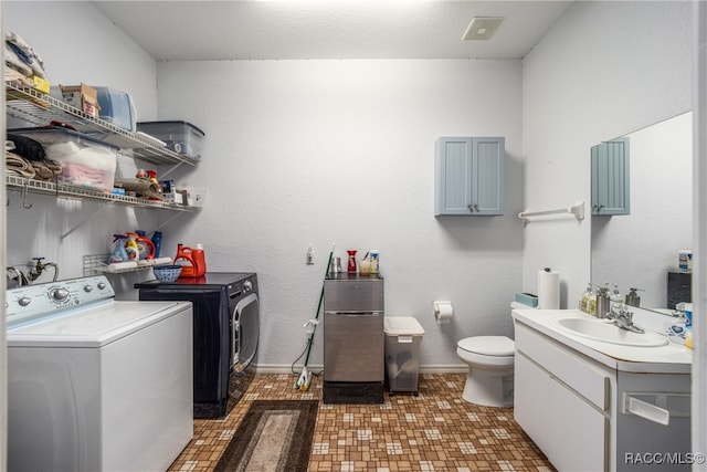 laundry area featuring washer and clothes dryer, dark tile patterned floors, and sink