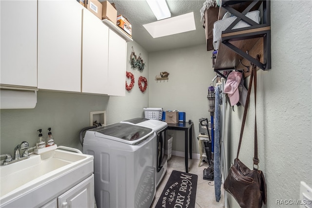 laundry area with a skylight, sink, cabinets, a textured ceiling, and washer and clothes dryer