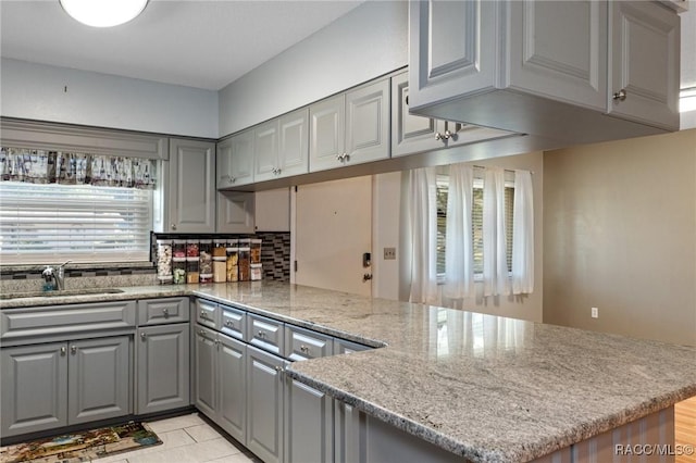 kitchen featuring gray cabinetry, plenty of natural light, kitchen peninsula, and sink