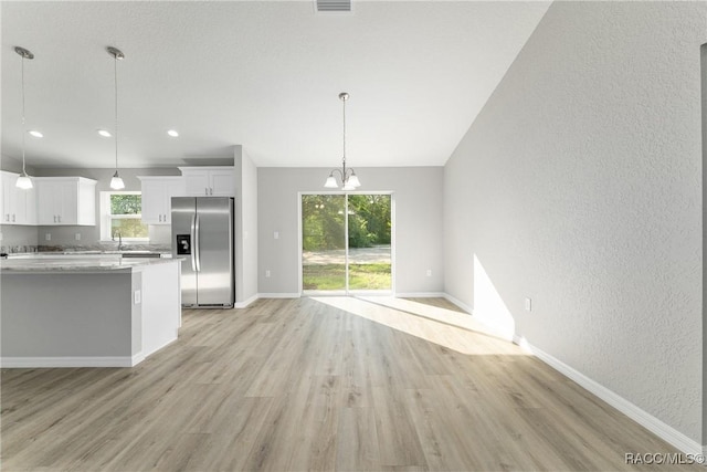 9065 N Arcadia Way, Citrus Springs, FL 34434 - kitchen with light wood-style flooring, baseboards, white cabinetry, stainless steel fridge, and a chandelier